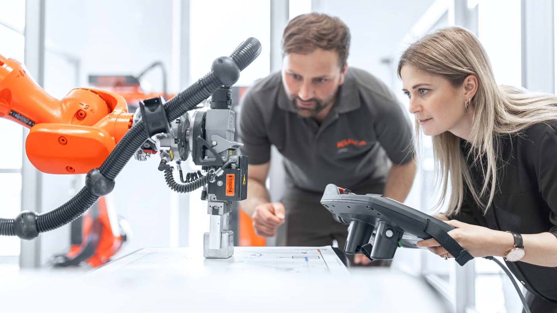 KUKA Mitarbeiter und Kundin mit Steuergerät am Roboter