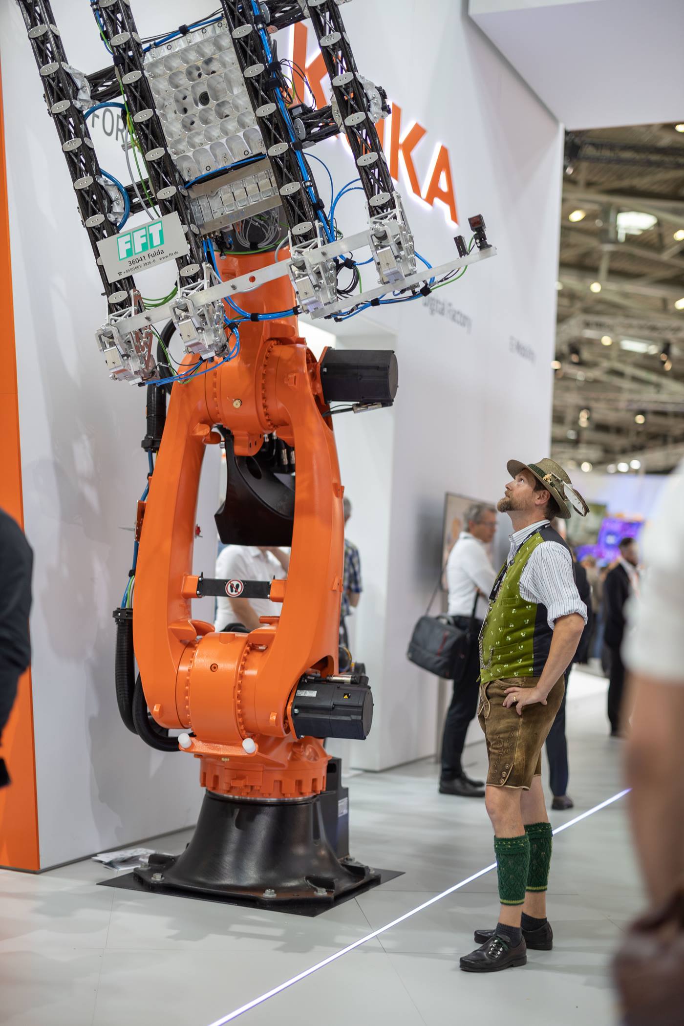 automatica 2022 trade fair visitor in lederhosen looks at KUKA robot at the KUKA booth 