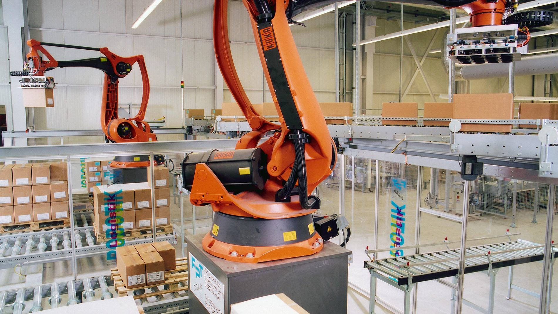 Roboter in der Produktion von Körperpflegeprodukten: Zwei KUKA Roboter palettieren Kisten in einer Produktionshalle. 
