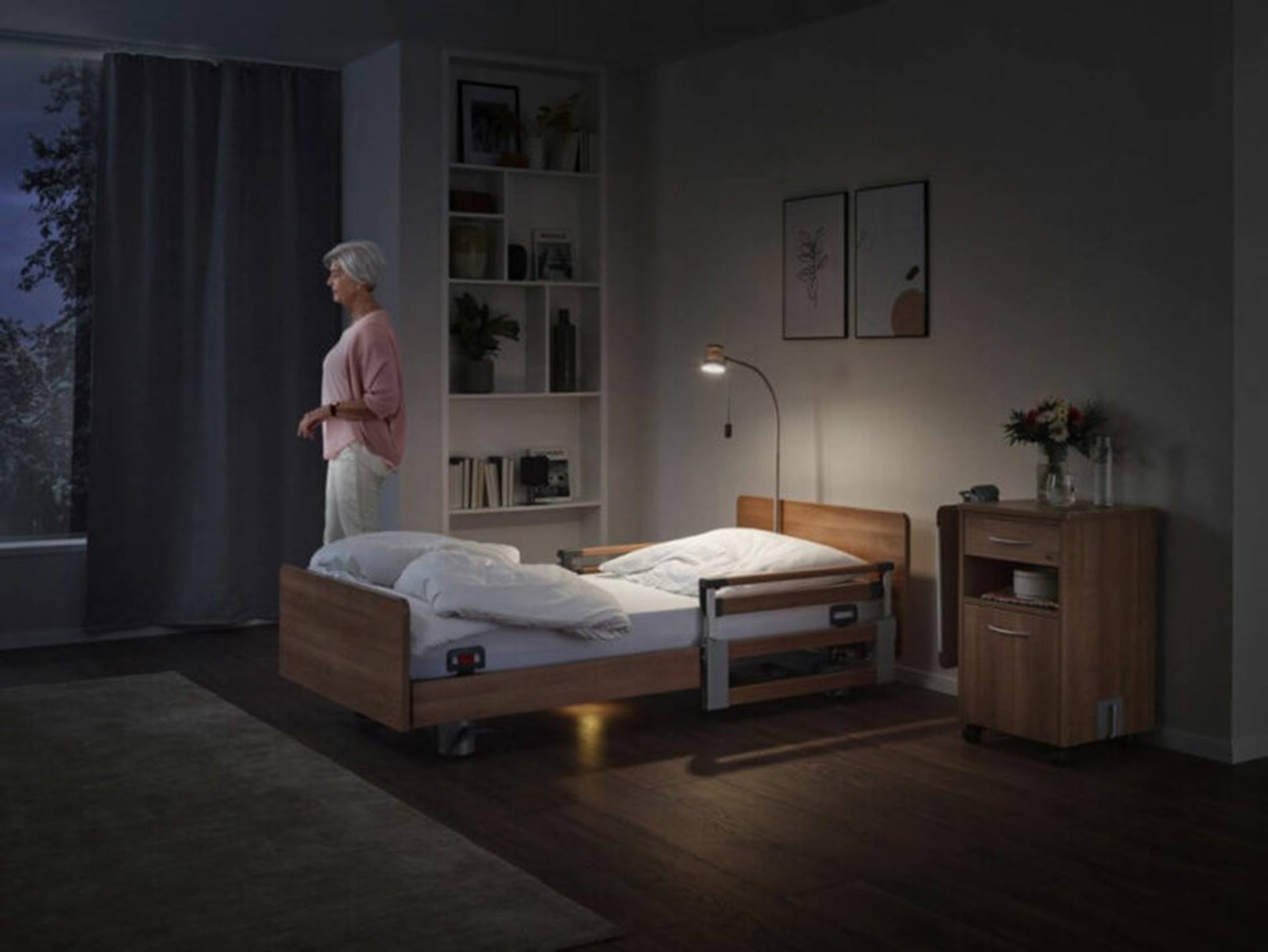 A woman stands in a room next to a bed: grandcentrix & Device Insight's narrowband IoT solution transforms STIEGELMEYER's hospital and care beds into smart products. 
