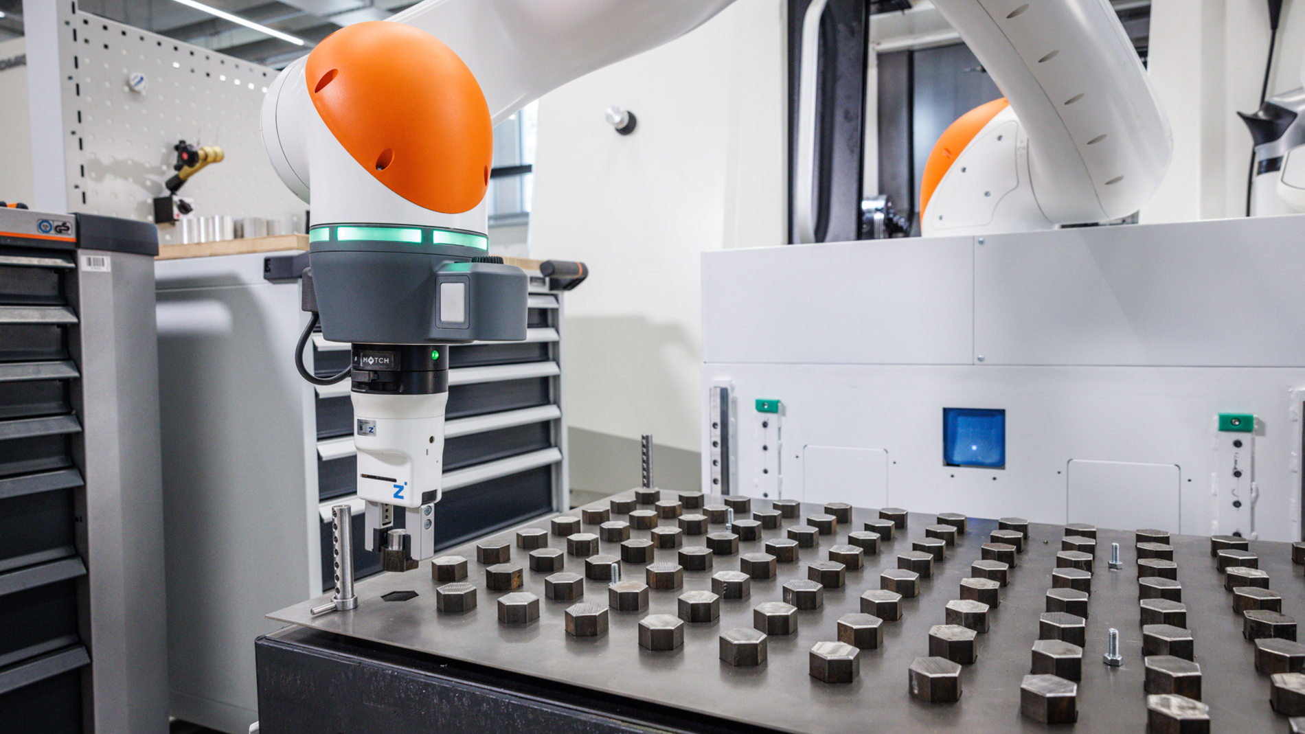 Cobot greift Werkstück, um damit eine CNC-Fräsmaschine zu bestücken.