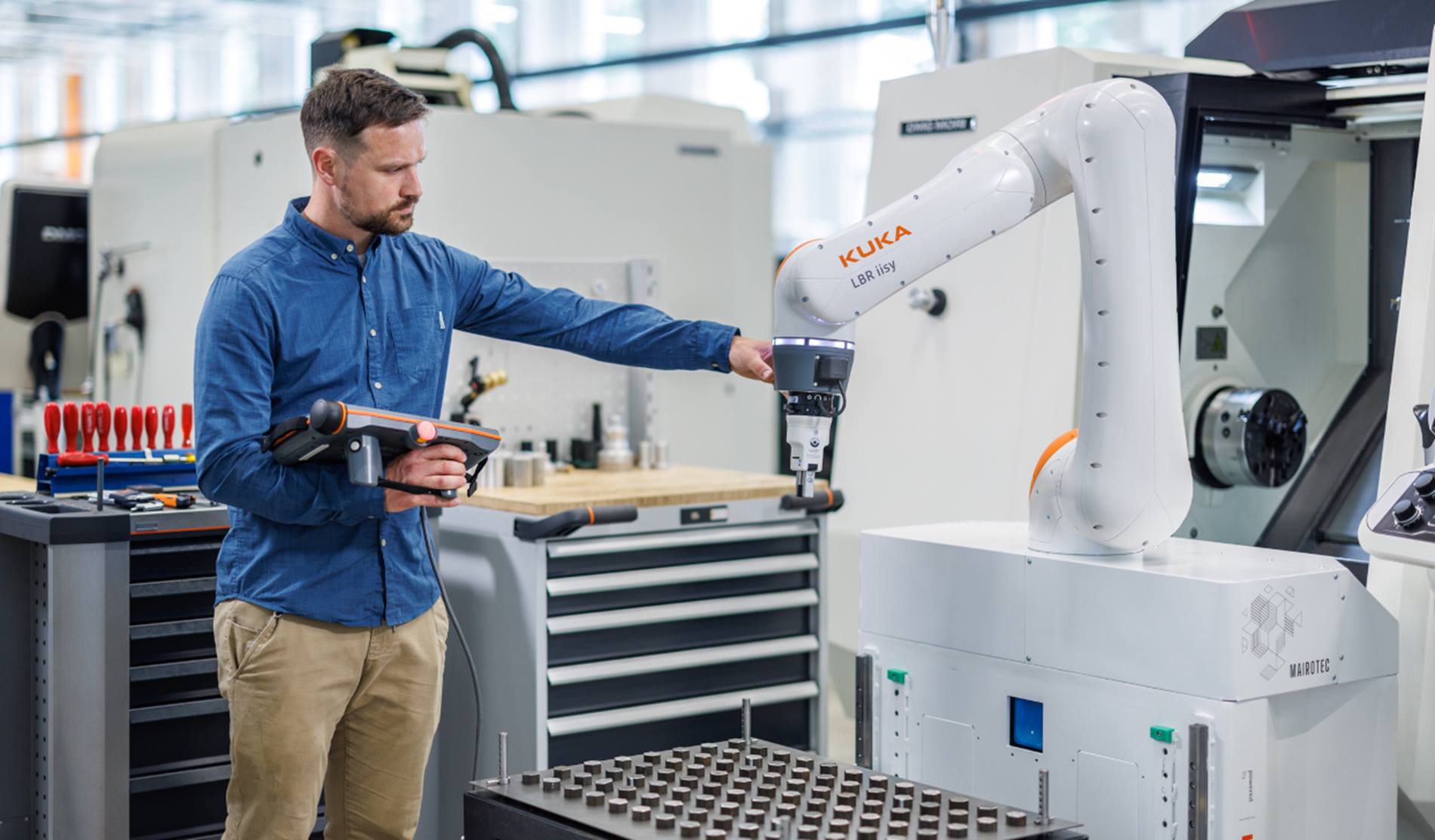 Cobot wird von einem Mitarbeiter in die richtige Position geführt.