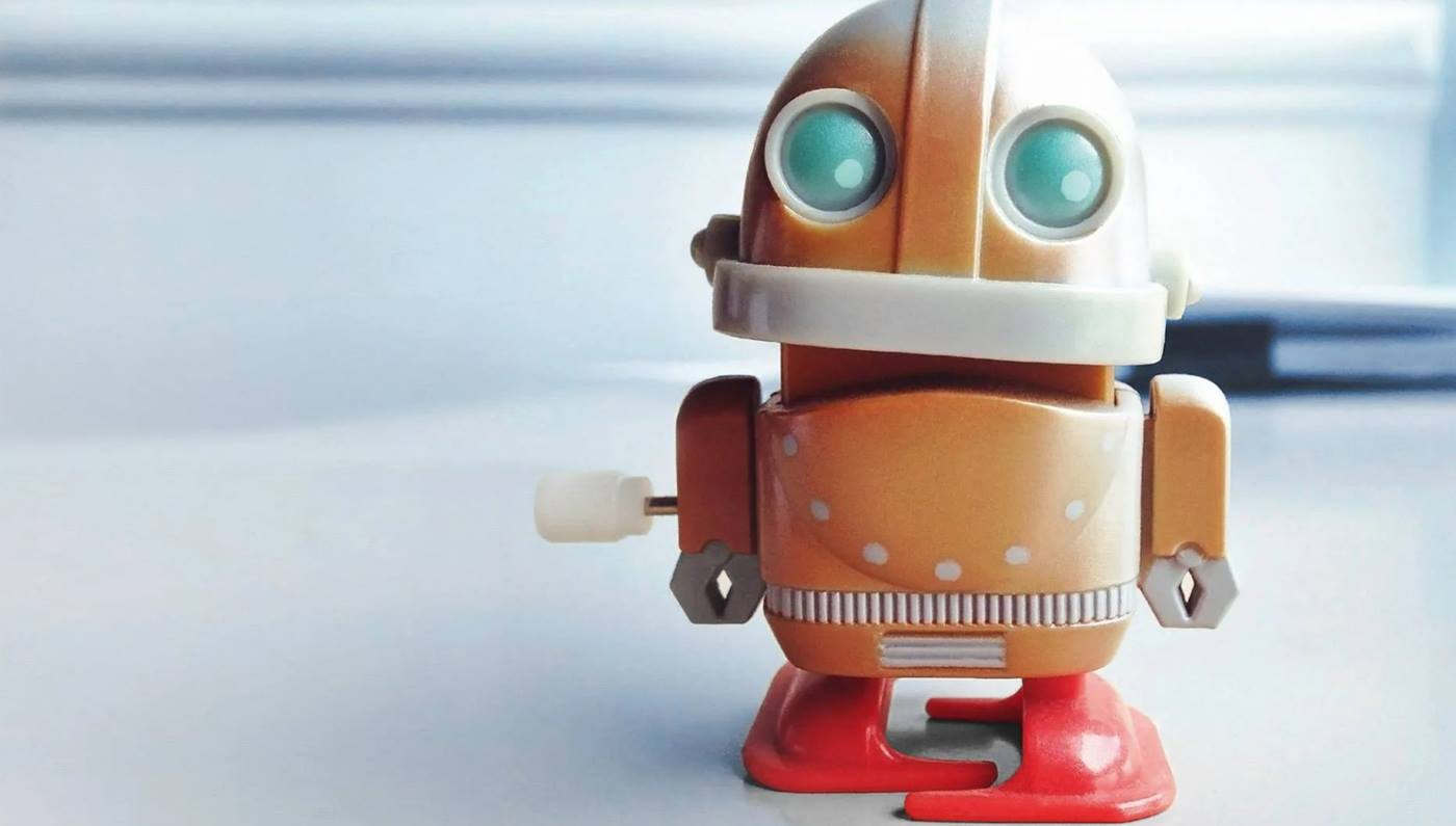Toy-Roboter orange stands on a desk and stares at the camera