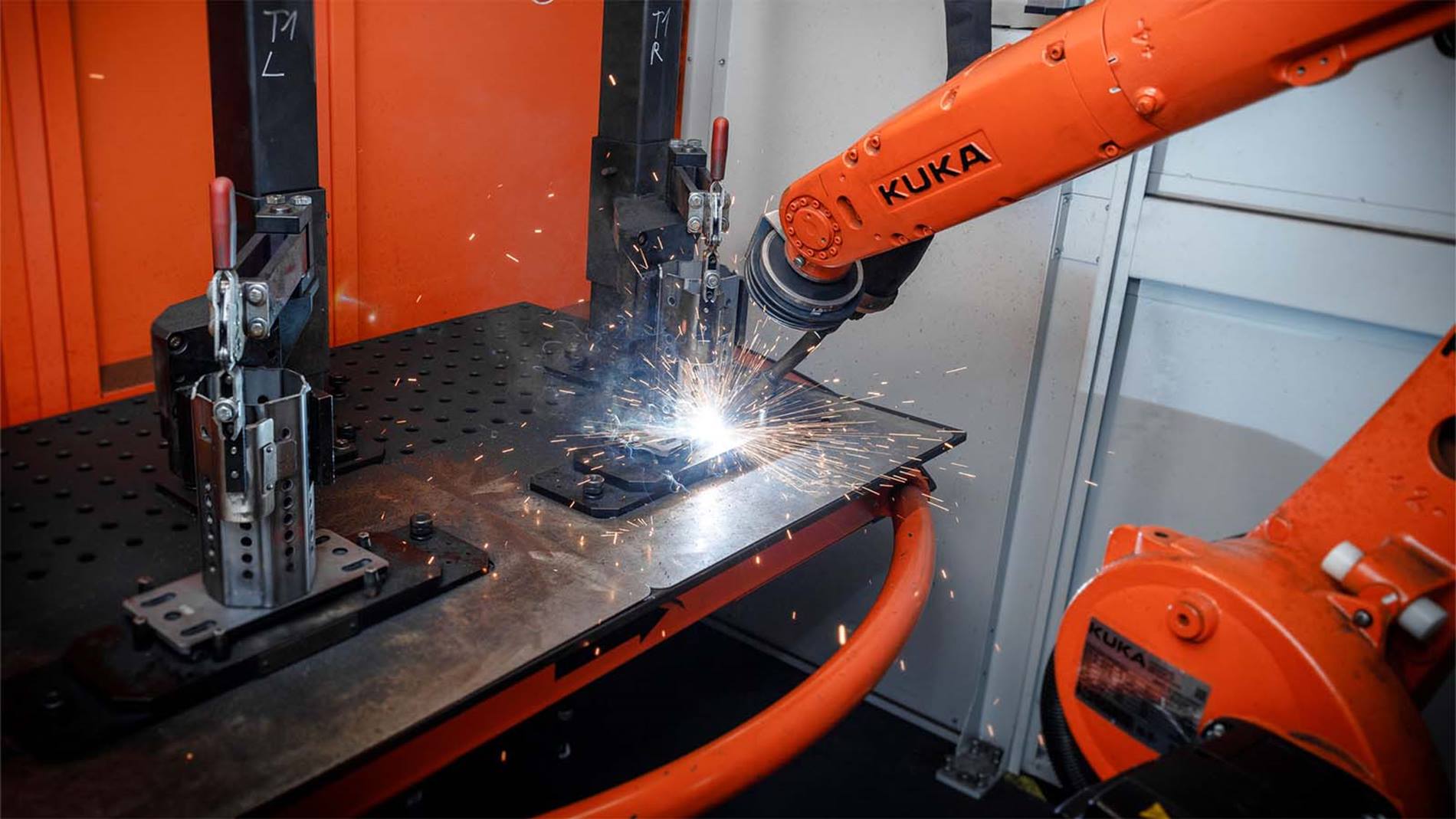 Der KUKA Roboter verbindet mithilfe des Schweißgeräts das achteckige Prisma mit einer Platte aus Stahl