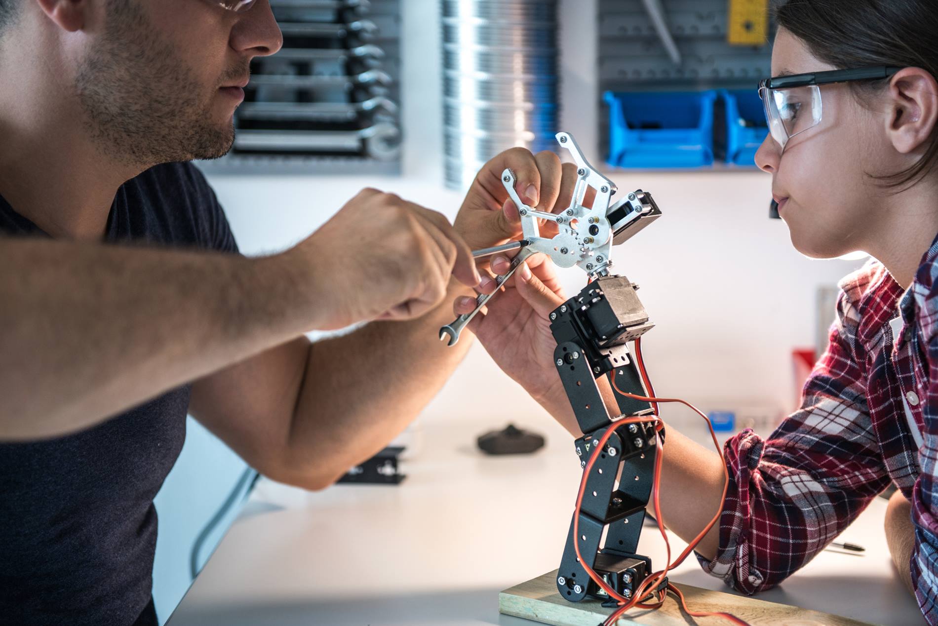 Man and girl working together on robot hand 