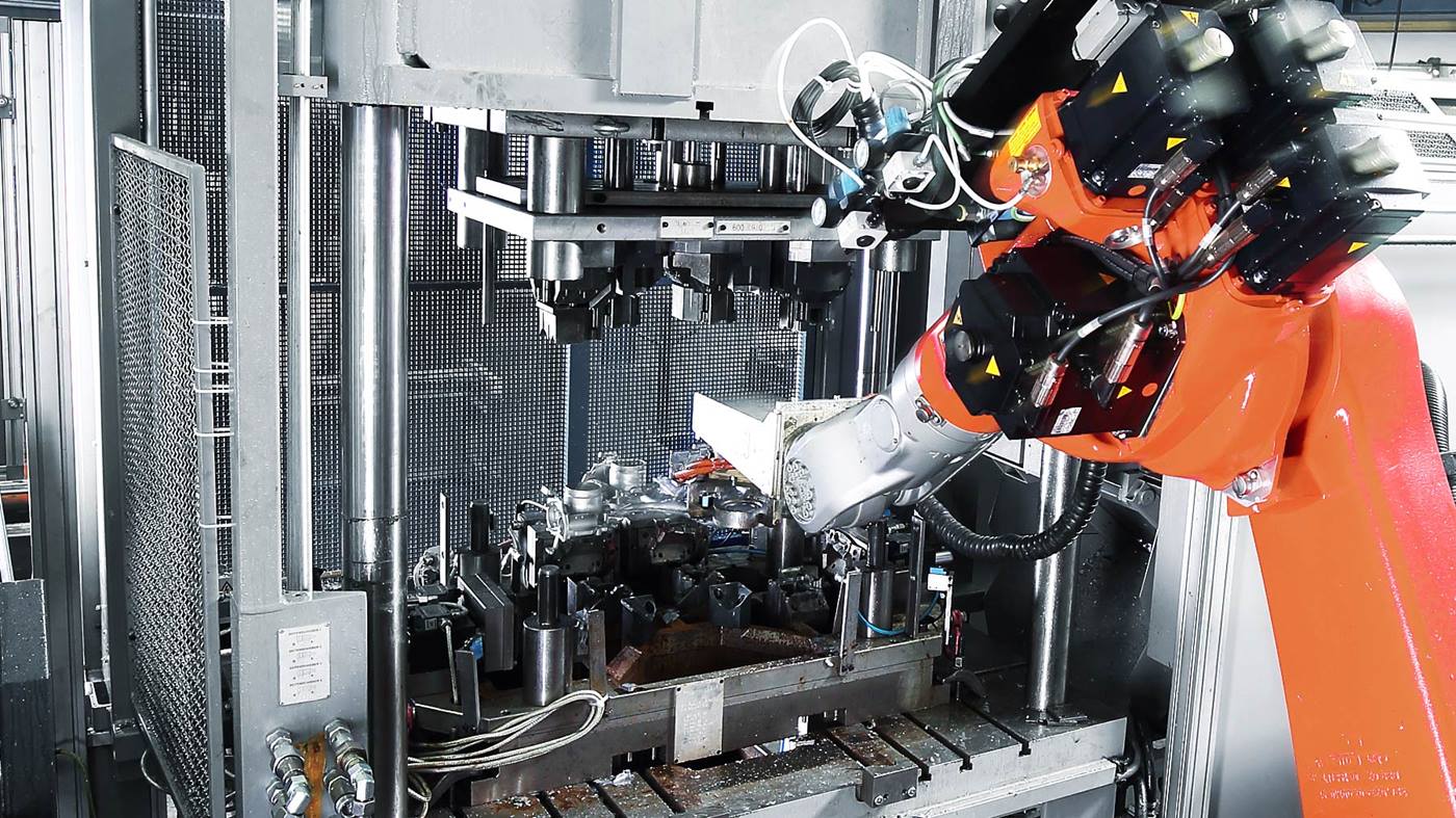 Der Roboter legt das Gußteil zum Trennnen und Entgraten in die Presse