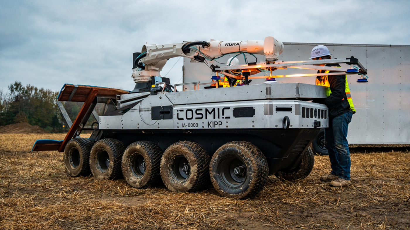 An autonomous mobile platform carrying a KUKA robot supports outdoor solar panel installation across uneven terrain.