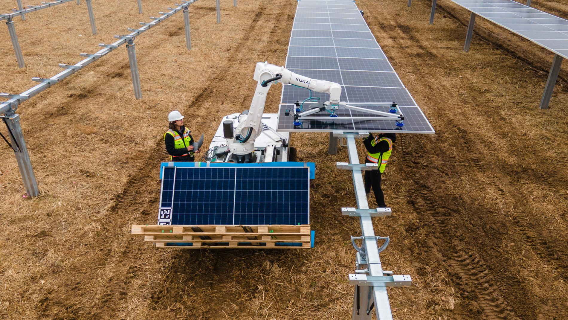 A KUKA industrial robot precisely places a solar panel onto a mounting structure in a utility-scale solar installation