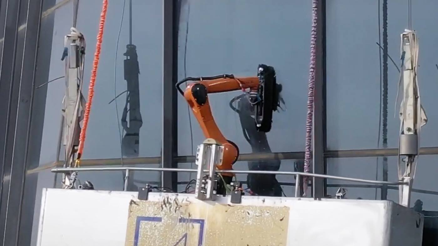 Un robot lavavetri lava vetri sullo sfondo di edifici a più piani