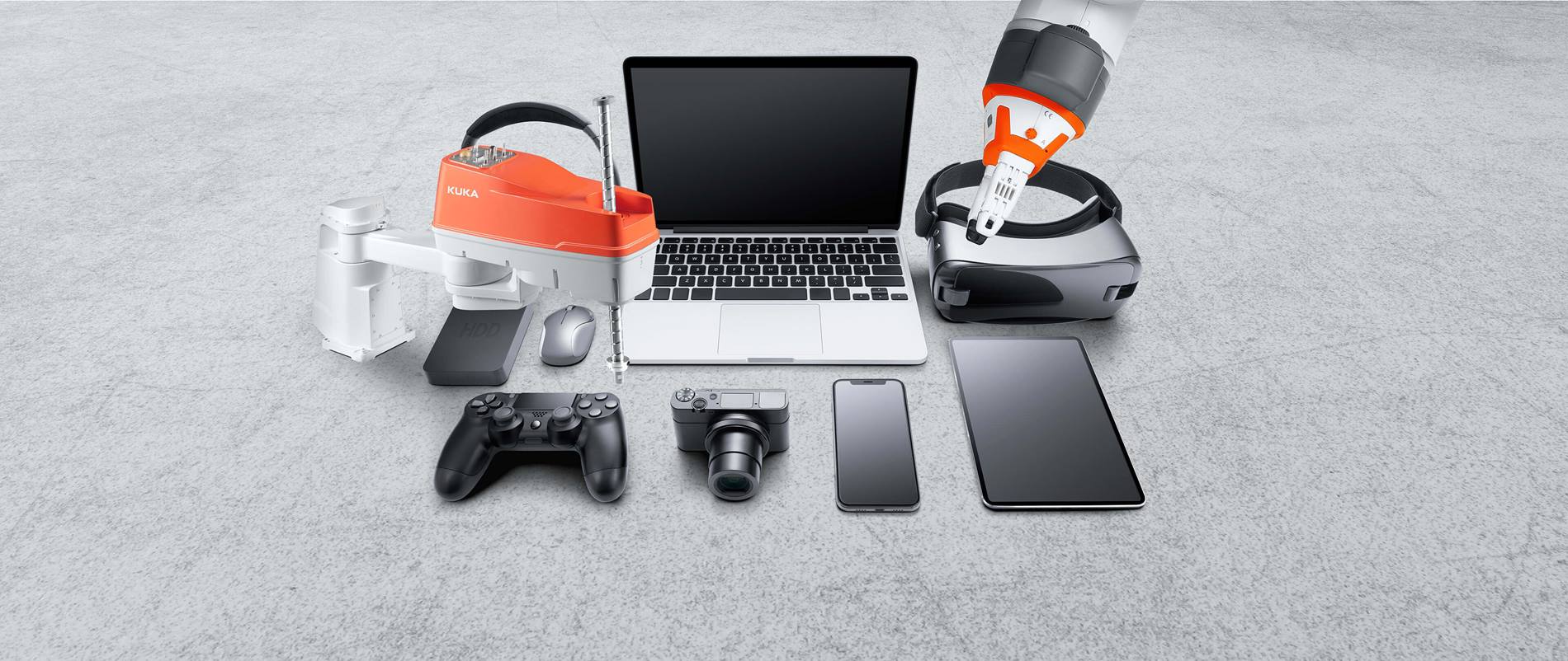 Verschiedene Geräte der Unterhaltungselektronik wie Kopfhörer, Laptop, Digitalkamera, Handy, Tablet, VR-Brille, Maus, externe Festplatte, Spielkonsole und zwei KUKA Roboter
