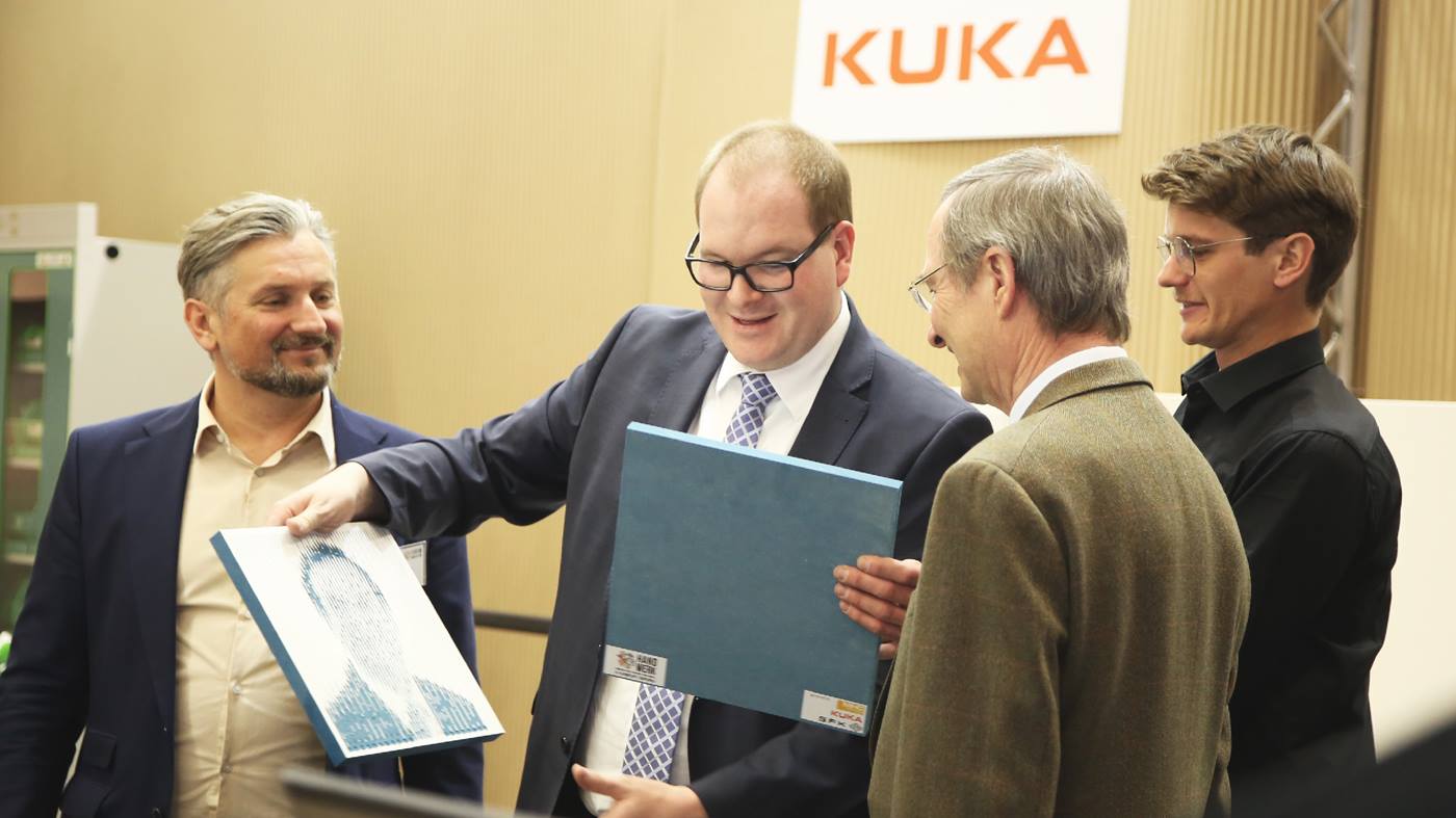 Hier sehen Sie, wie Herr Dr. Christoph Leitl, Präsident der Wirtschaftskammer Österreich, ein gefrästes Portrait von einem KUKA Roboter erhält.